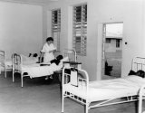 Nalerigu. Baptist Hospital; ward, Mrs. Robert F. Goldie, missionary nurse checking a patients pulse