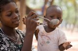 A mother feeds her malnourished child a high-protein porridge at Koko Duu, the nutritional rehabilitation center